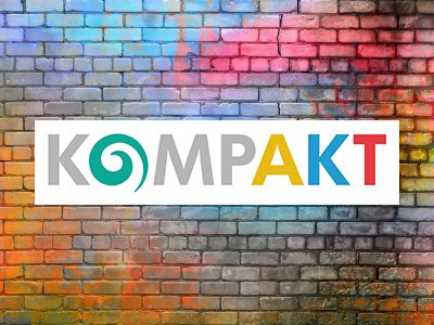 Bunte Backsteinmauer mit KompAKT Logo