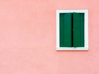 Ein Fenster mit grünen Fensterläden an einer rosa Wand